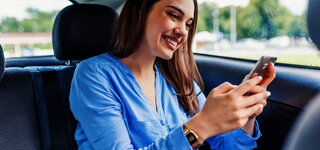 Lächelnde Kundin mit Smartphone im Fahrzeug @ 
