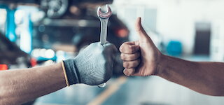 Werkstatt-Team des Autohauses in Hanstedt: Hand mit Schraubenschlüssel und Daumen nach oben @ 